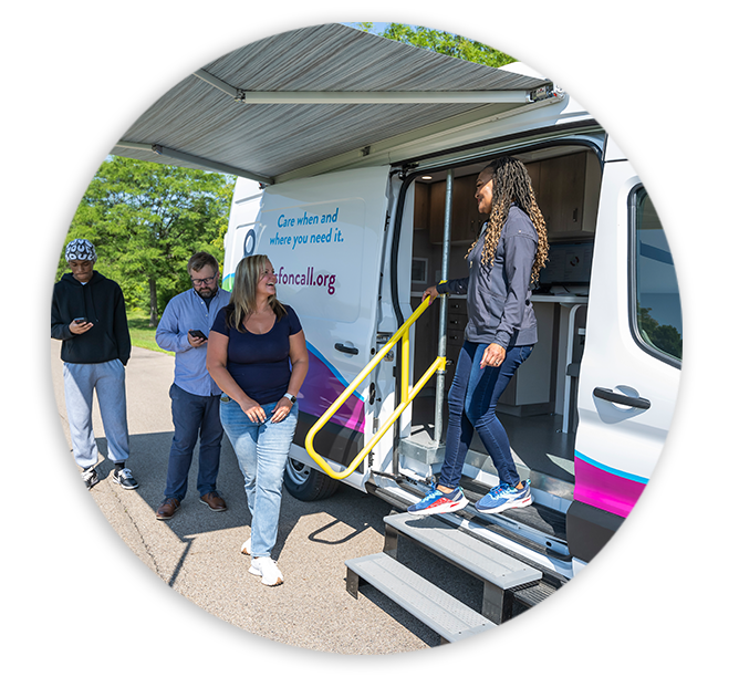 A diverse group of people standing near a white OSF OnCall mobile medical van with an extended awning and stairs, illustrating accessible community healthcare.