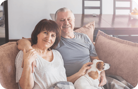 A happy elderly couple relaxing at home on their sofa with their pet dog.