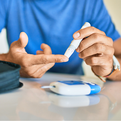 Close-up of a person using a lancet device to prick their finger for a blood glucose test.