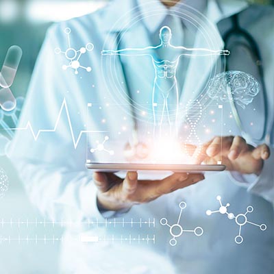 Close-up of a doctor in a white lab coat using a tablet that projects futuristic blue medical icons, including a human silhouette, DNA strands, and a heart rate monitor.