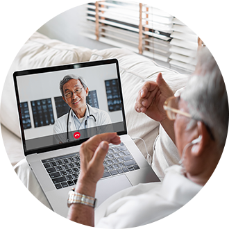 An elderly man at home having a telehealth video consultation with a doctor on his laptop.