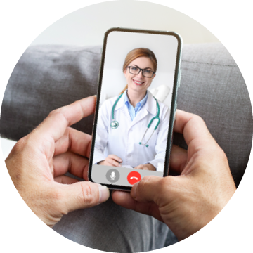 A person holding a smartphone during a video call with a smiling doctor wearing glasses and a stethoscope, illustrating a telehealth appointment.